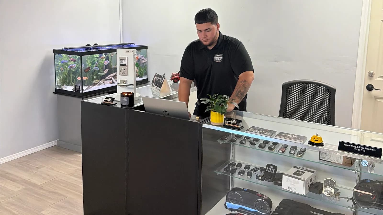 A technician at the front counter of The Locksmith Shop in South Tampa, beside a deadbolt and lever display and a glass case of keypad locks